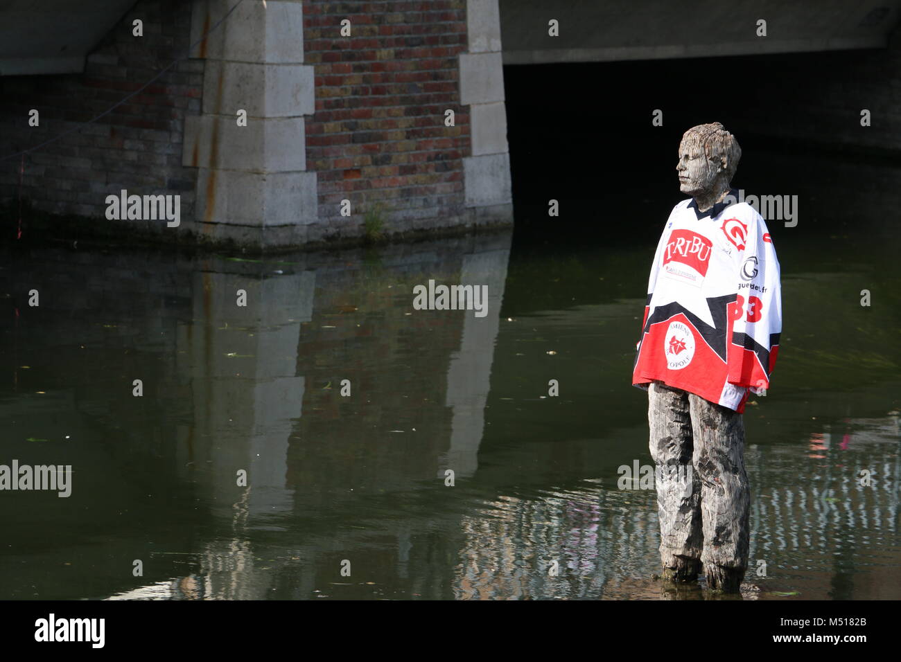 Statua in legno "L'homme sur sa bouée' da Stephan Balkenhol, Saint-Leu, Amiens, Francia - travestiti da studenti con una maglietta da una squadra sportiva locale Foto Stock