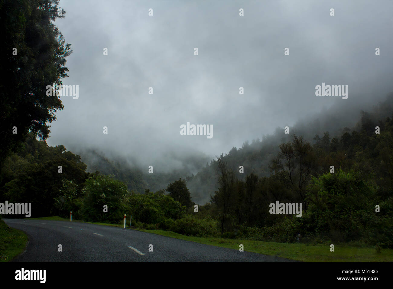 Strada girate con un suggestivo paesaggio naturale con la nebbia e il cielo in tempesta Foto Stock