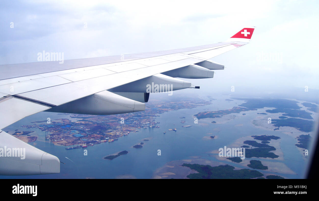 SINGAPORE - APR 1st, 2015: vista dal cloud, paesaggio, isole e ala di aeroplano - vedere attraverso la finestra aereo prima di atterrare a Singapore aeroporto internazionale peccato Foto Stock