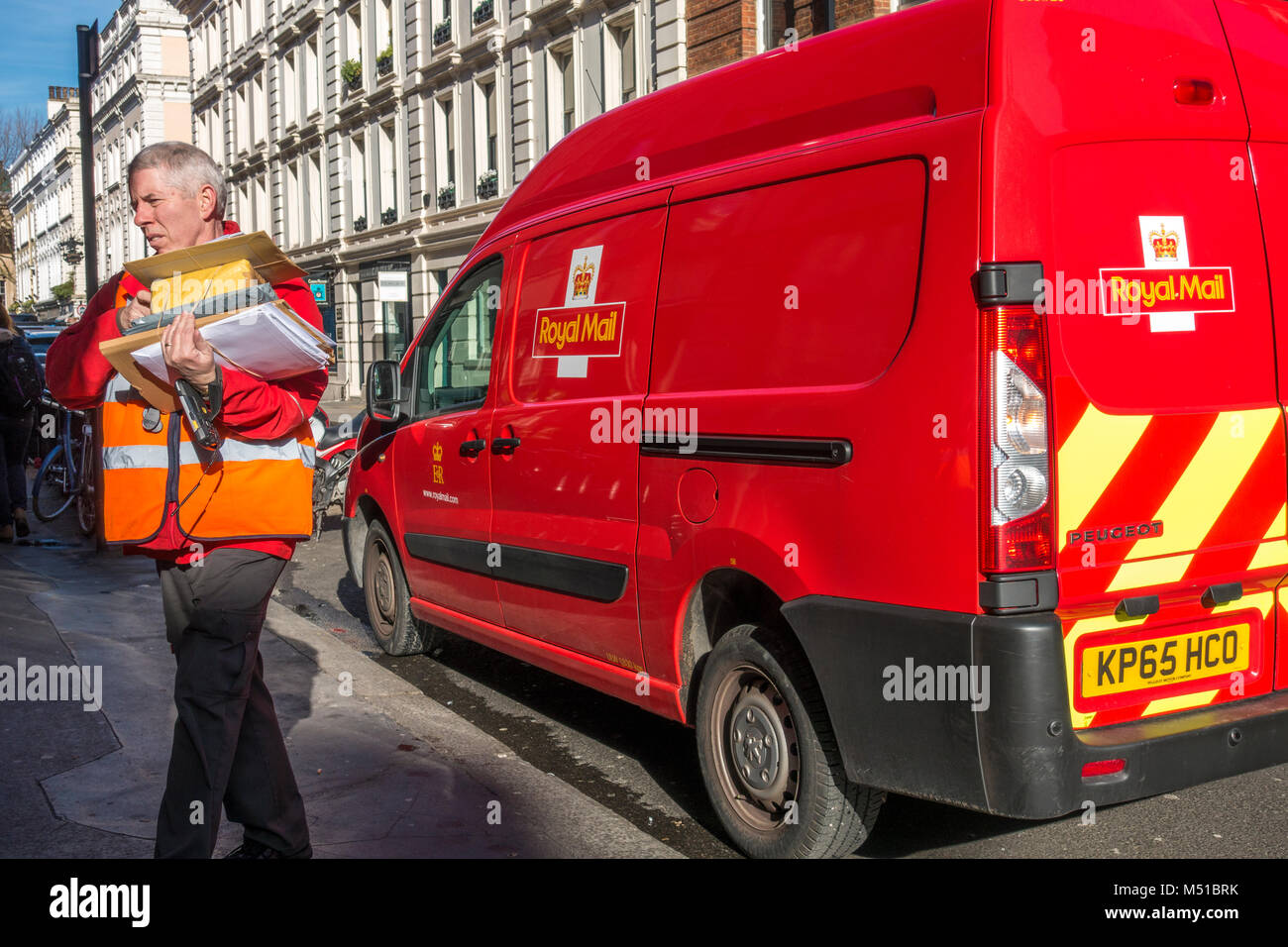 Royal Mail adulto maschio / uomo driver di consegna e van, la consegna di lettere e pacchi nel centro di Londra su un luminoso giorno. Inghilterra, Regno Unito. Foto Stock