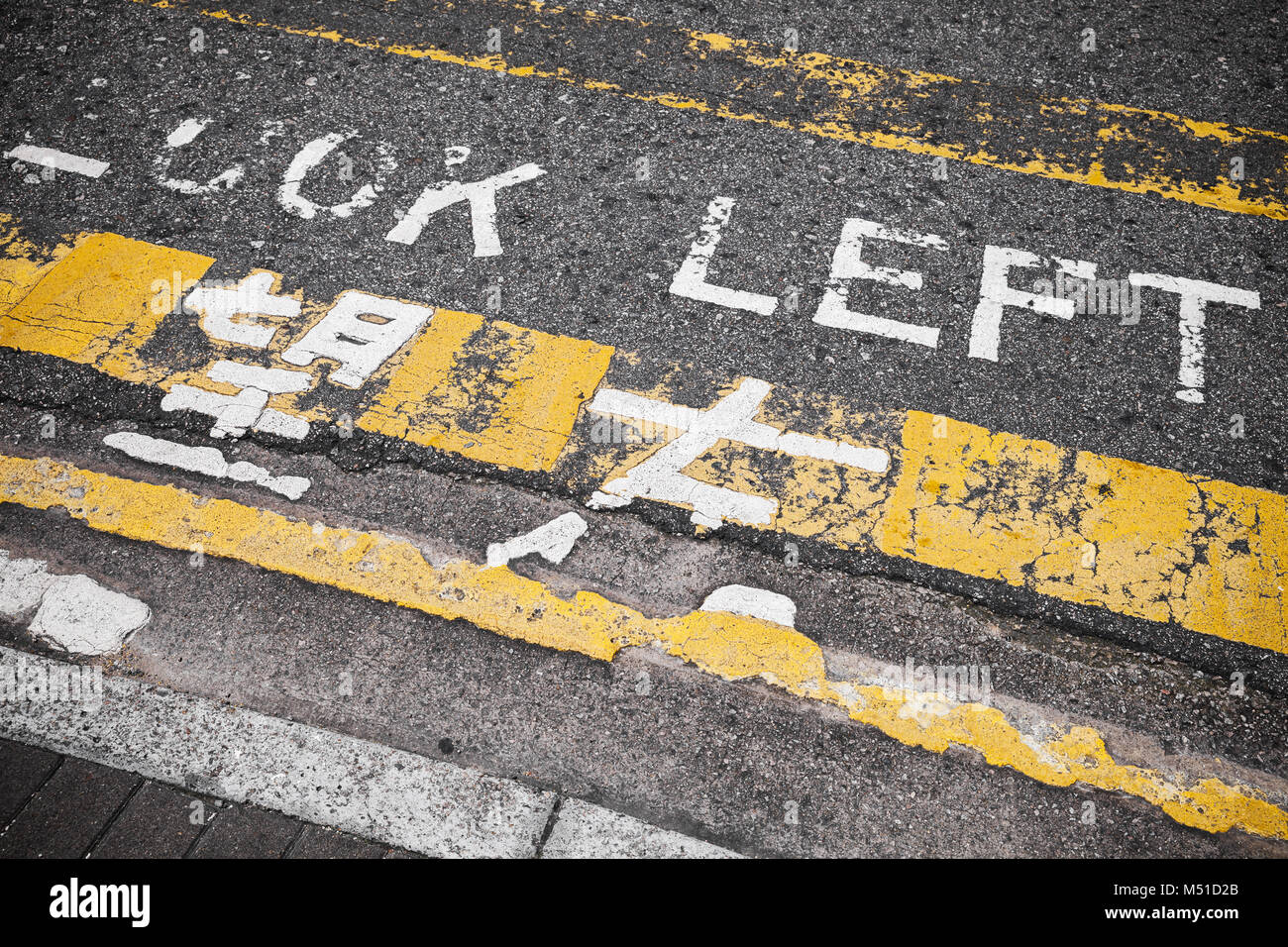 Guardare a sinistra. Attenzione la segnaletica stradale per pedoni mostra la direzione di avvicinamento nel traffico della città di Hong Kong Foto Stock