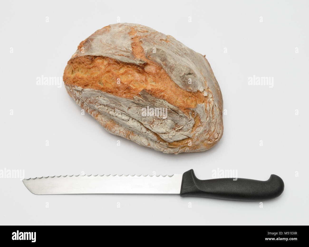 Il coltello e la pagnotta di pane fresco tagliato fuori isolati su sfondo bianco Foto Stock