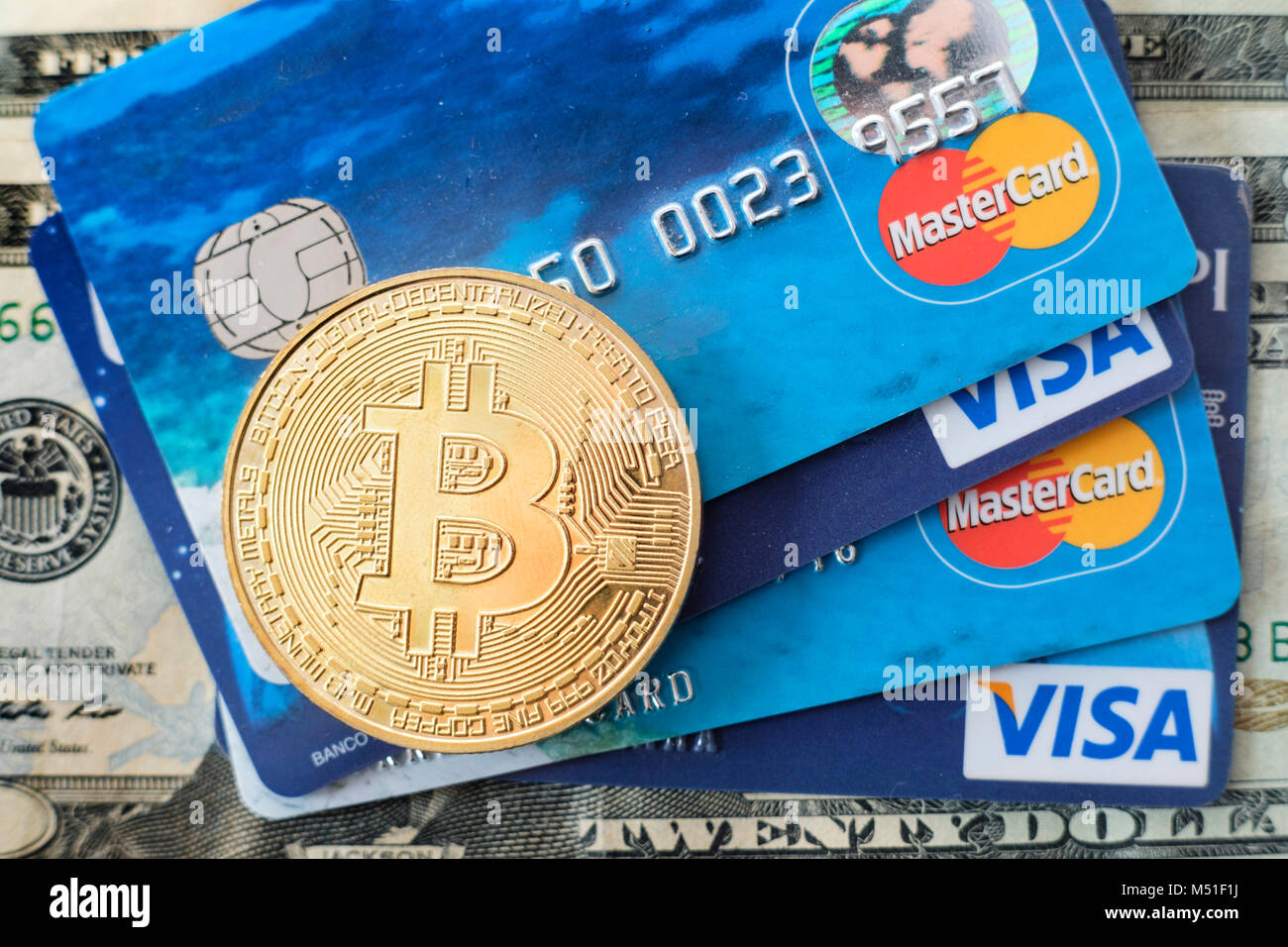 Token Bitcoin sulla sommità di VISA e MasterCard carte di credito e banconote americane Foto Stock