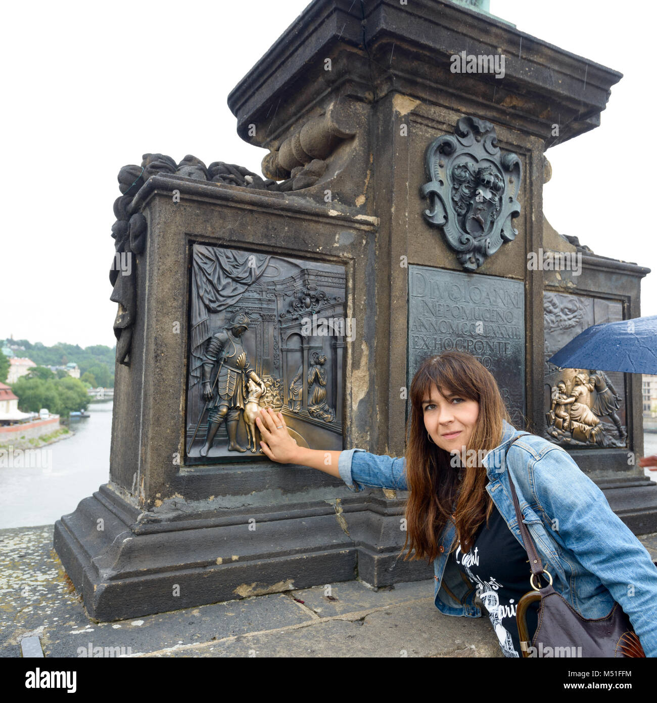 Ragazza di toccare le lastre di bronzo del piedistallo di San Giovanni di Nepomuk statua. Essa è la più antica statua sul Ponte Carlo. La tradizione dice che w Foto Stock