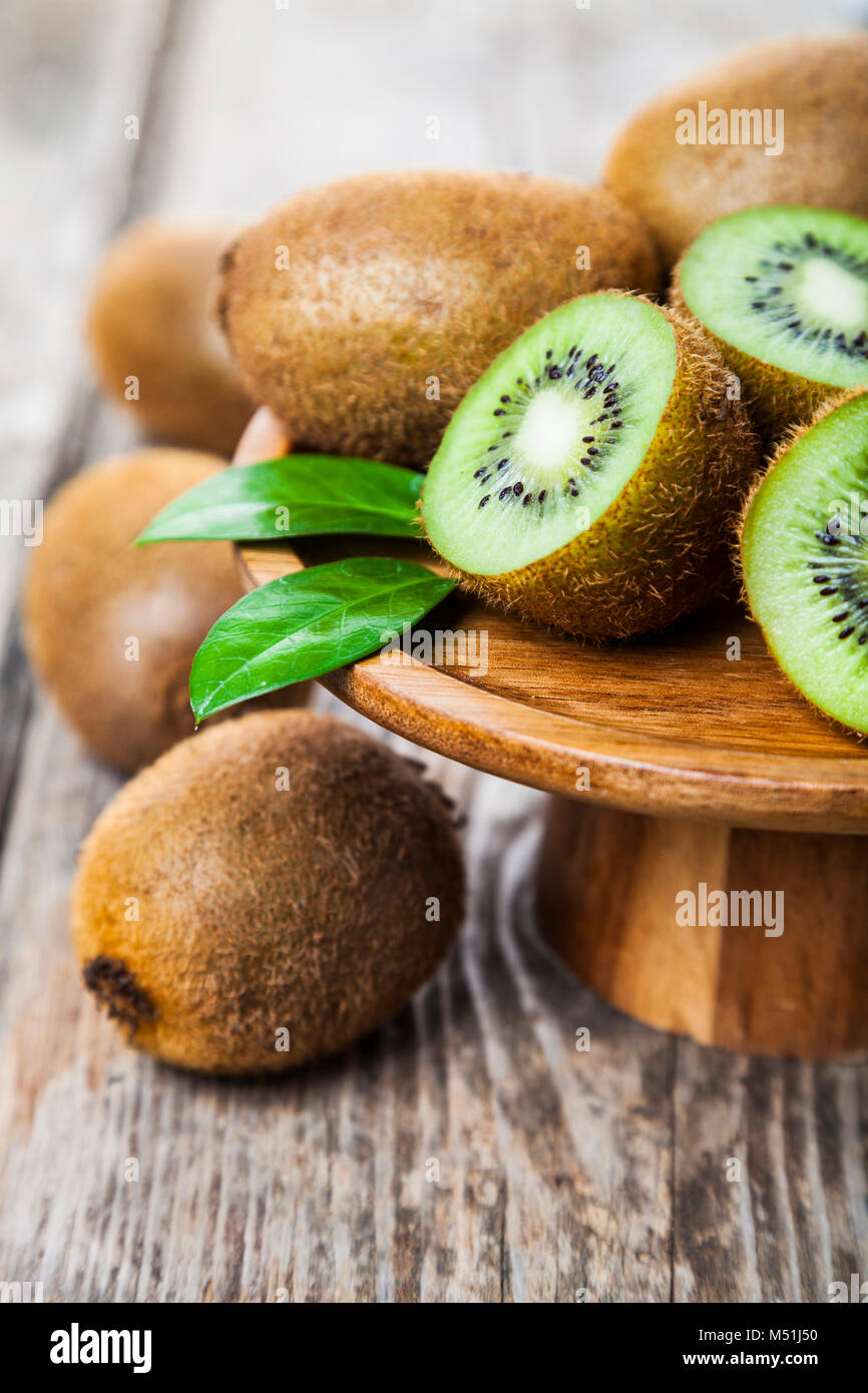 Ripe kiwi in un piatto di legno su un sfondo di legno. Mangiare sano. Foto Stock