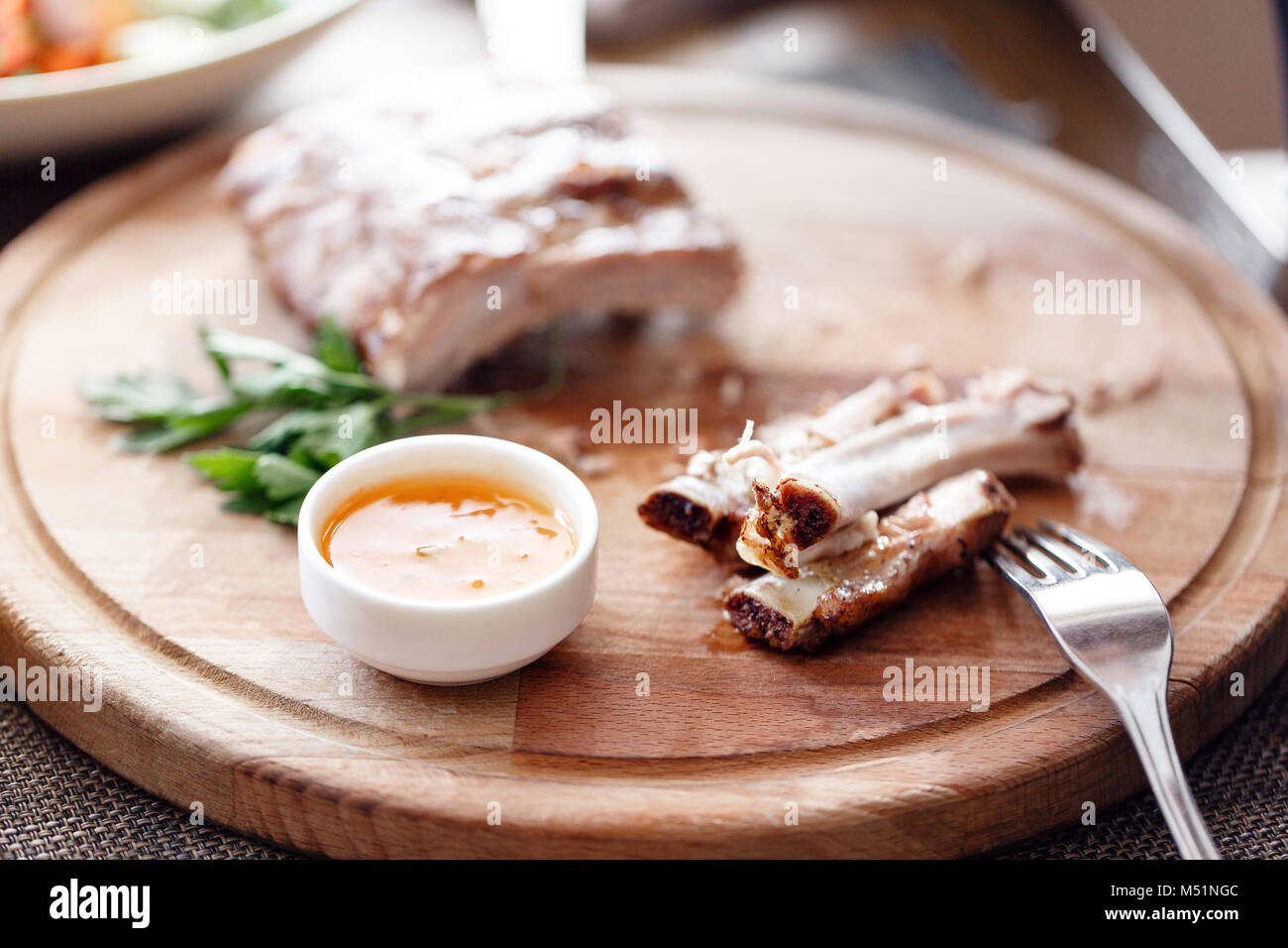 Le costole. l uomo nel ristorante con un coltello taglia grigliata di costolette di maiale. Servire su una tavola di legno. Foto Stock