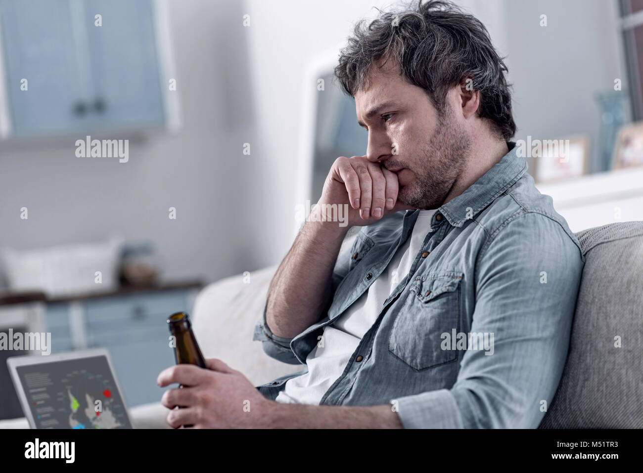 Uomo divorziato bere alcool mentre a pensare la sua vita miserabile Foto Stock