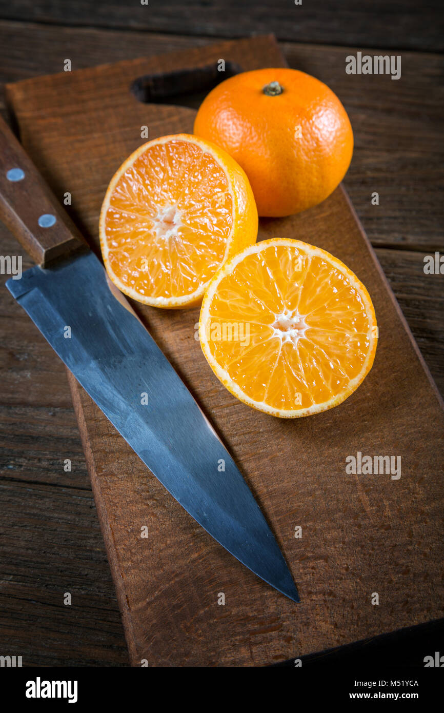 Tangerine del coltello di taglio su un vecchio tavolo closeup Foto Stock