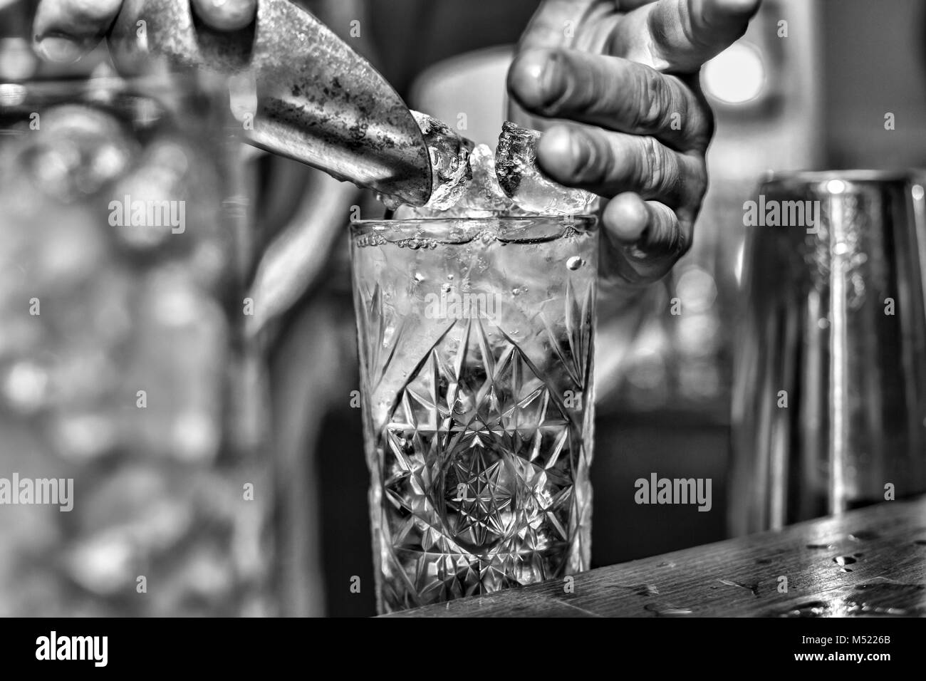 Barman mette il ghiaccio in un cocktail Foto Stock