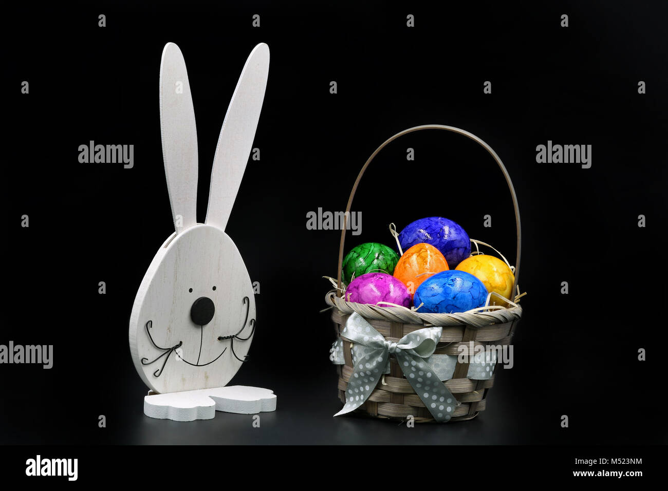 Uova di Pasqua nel cestello con coniglio isolato su sfondo nero Foto Stock