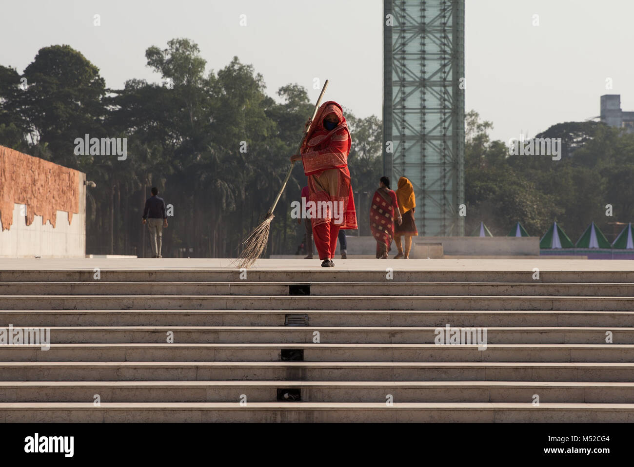 Una donna che spazza i passaggi presso il Parco di Indipendenza. L'indipendenza è stata data al Bangladesh il 26 marzo 1971. Dacca, capitale del Bangladesh si trova lungo la sponda est del fiume Buriganga nel cuore del delta del Bengala. La città è un microcosmo di tutto il paese, con diversi religiosi e comunità etniche. Dacca è economico, centro culturale e politico del Bangladesh ed è un importante centro finanziario dell Asia del Sud. È uno del mondo più popolosa città con una popolazione di 18.89 milioni di persone in la maggiore area di Dhaka. Foto Stock
