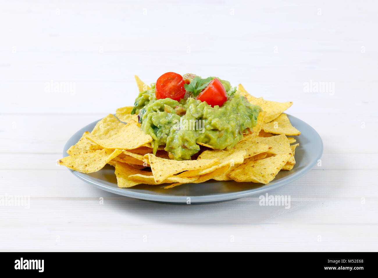 La piastra di granoturco tortilla chips con il guacamole dip su sfondo bianco Foto Stock