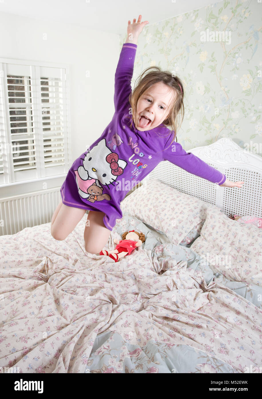 4 anno vecchia ragazza di saltare sul letto dei genitori Foto Stock