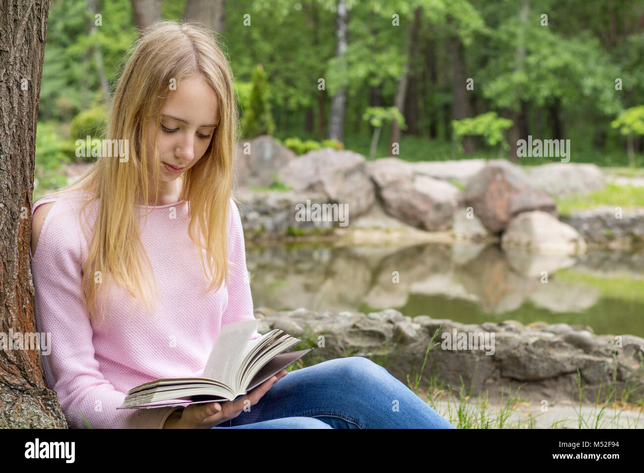 Carino teenage-girl per leggere un libro nel parco della città Foto Stock