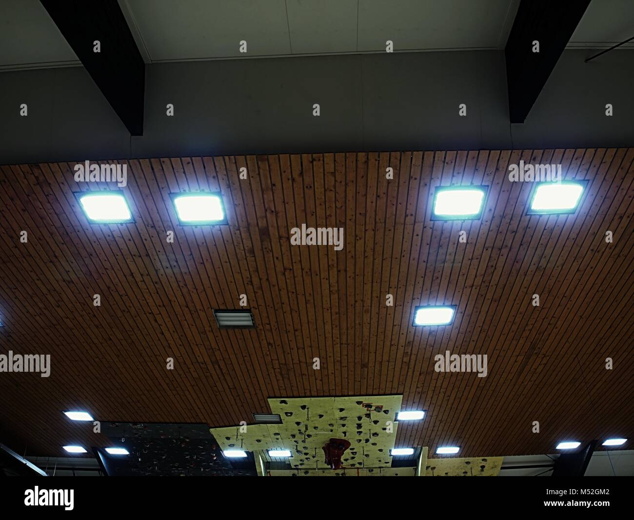 Soffitto luminoso di mattonelle quadrate. Soffitto in legno con pannelli di illuminazione. Le lampade fluorescenti sul soffitto moderno. Foto Stock