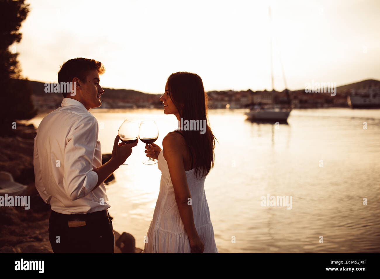 Coppia romantica bere il vino al tramonto in un molo sul mare.Romance.Due persone aventi una romantica serata con un bicchiere di vino vicino al mare.godendo Foto Stock