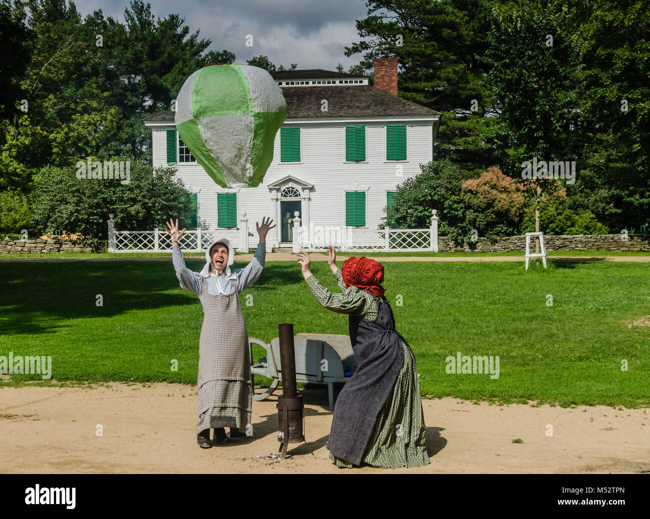 Due donne in costume di Old Sturbridge Village, riempimento a casa in mongolfiera ad aria calda in un antico giocattolo di dimostrazione. Foto Stock