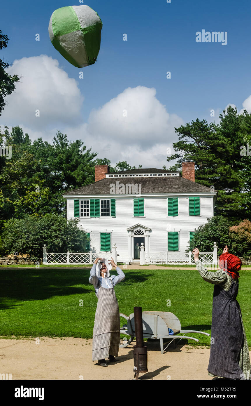 Due donne in costume di Old Sturbridge Village, riempimento a casa in mongolfiera ad aria calda in un antico giocattolo di dimostrazione. Foto Stock