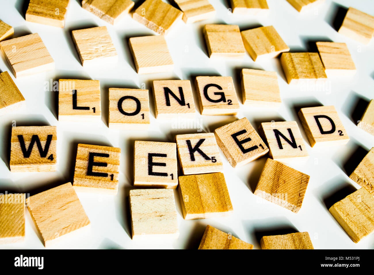 Parola lungo weekend. Scrabble in legno lettere l'ortografia della parola lungo weekend su bianco backround. Foto Stock
