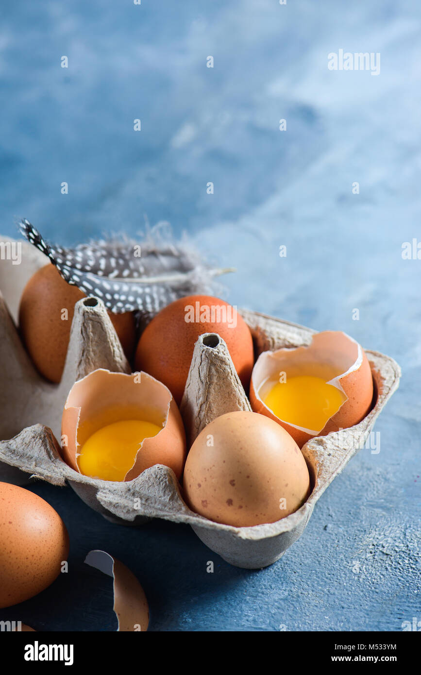 Materie le uova di gallina in craft carton, pack. Close-up con copia spazio. Guscio rotto con tuorlo visibile. Foto Stock