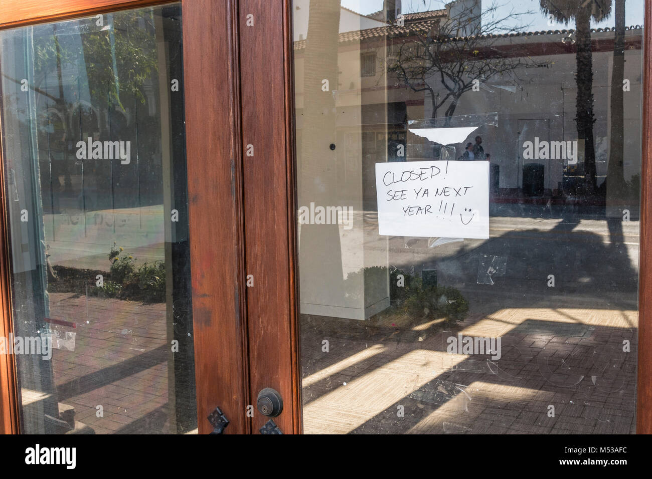 Un libro bianco il segno inviato su un negozio di vetro porta di ingresso con la notifica: 'See ya il prossimo anno!!!" con una faccina sorridente. Il negozio era una specialità st Foto Stock