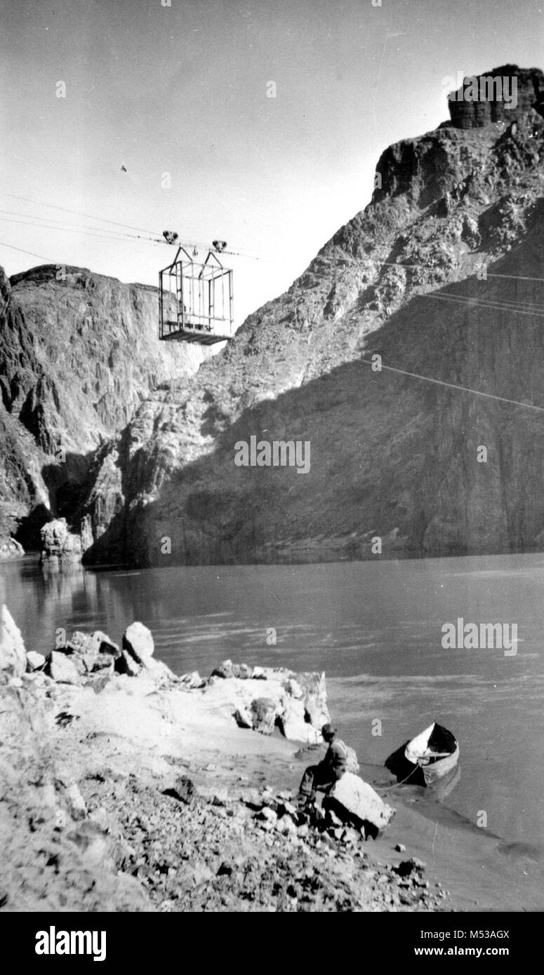 Cavo di ruggine e del tram auto oltre il Fiume Colorado. Uomo seduto a terra con una piccola barca di tela (al di sotto del cavo.) circa 1911. Raccolta della ruggine. Grand Canyon Parco Nat storica sul fiume foto. Foto Stock