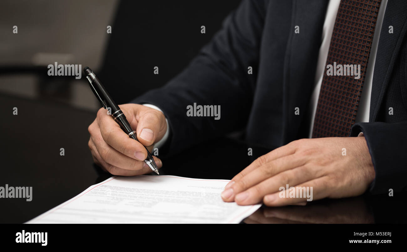 Ripresa macro di una mano di un uomo di affari di firma o la scrittura di un documento su un foglio di carta bianca utilizzando una fontana nibbed pen. Foto Stock