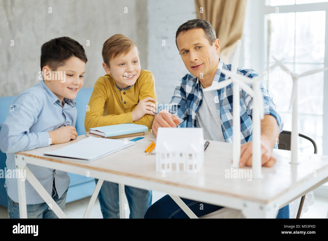 Piacevole padre spiegando la costruzione di turbine eoliche per i suoi figli Foto Stock
