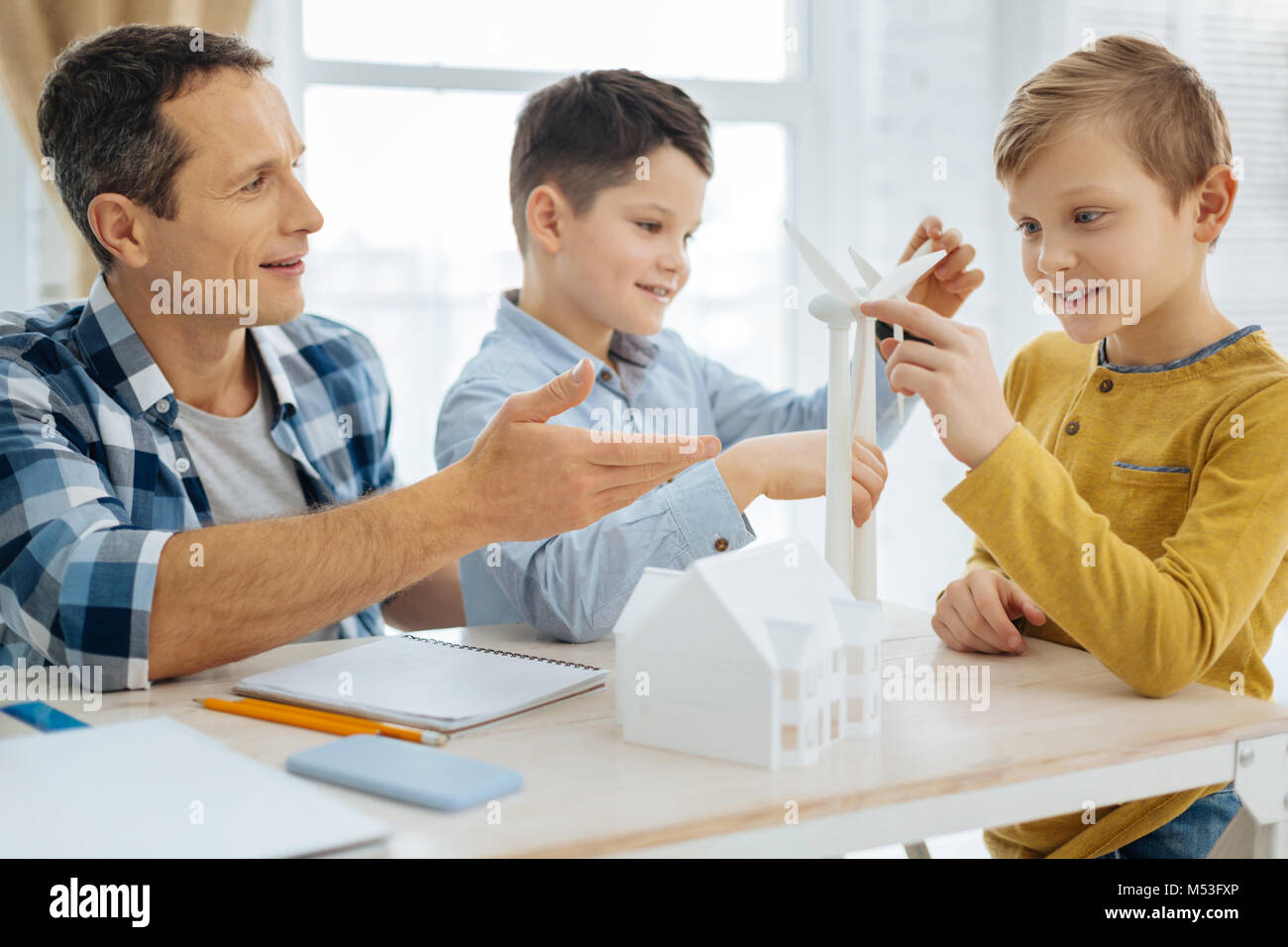 Upbeat boys scrutare turbina eolica modelli in ufficio dei padri Foto Stock