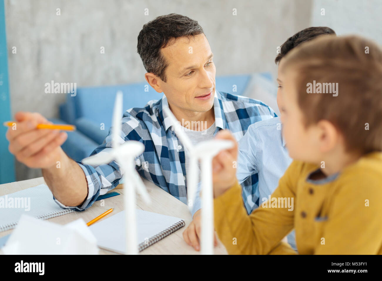Padre piacevole discutere i vantaggi delle turbine eoliche con figli Foto Stock
