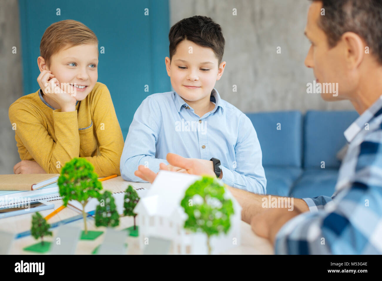 Ragazzi piacevole ascolto di padre dicendo circa il progetto ecologia Foto Stock