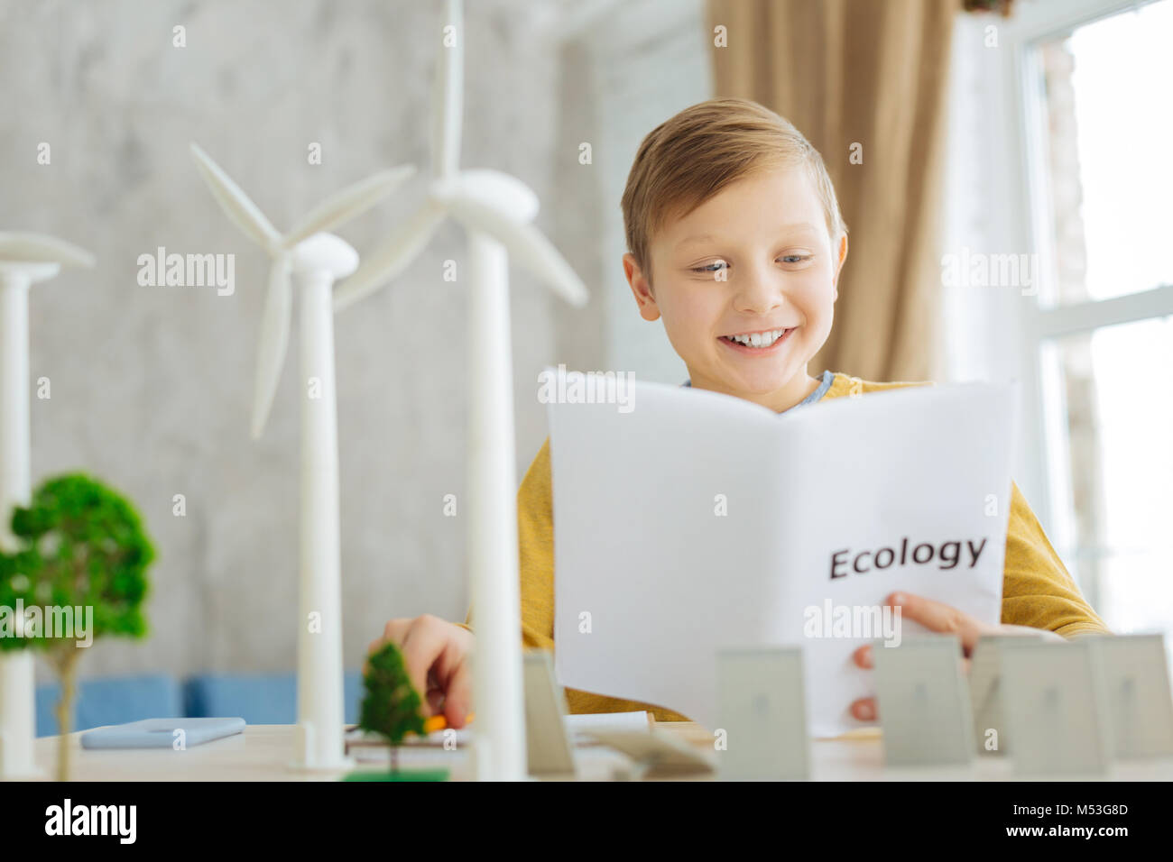 Allegro ragazzo lettura circa le fonti alternative di energia nel libro Foto Stock