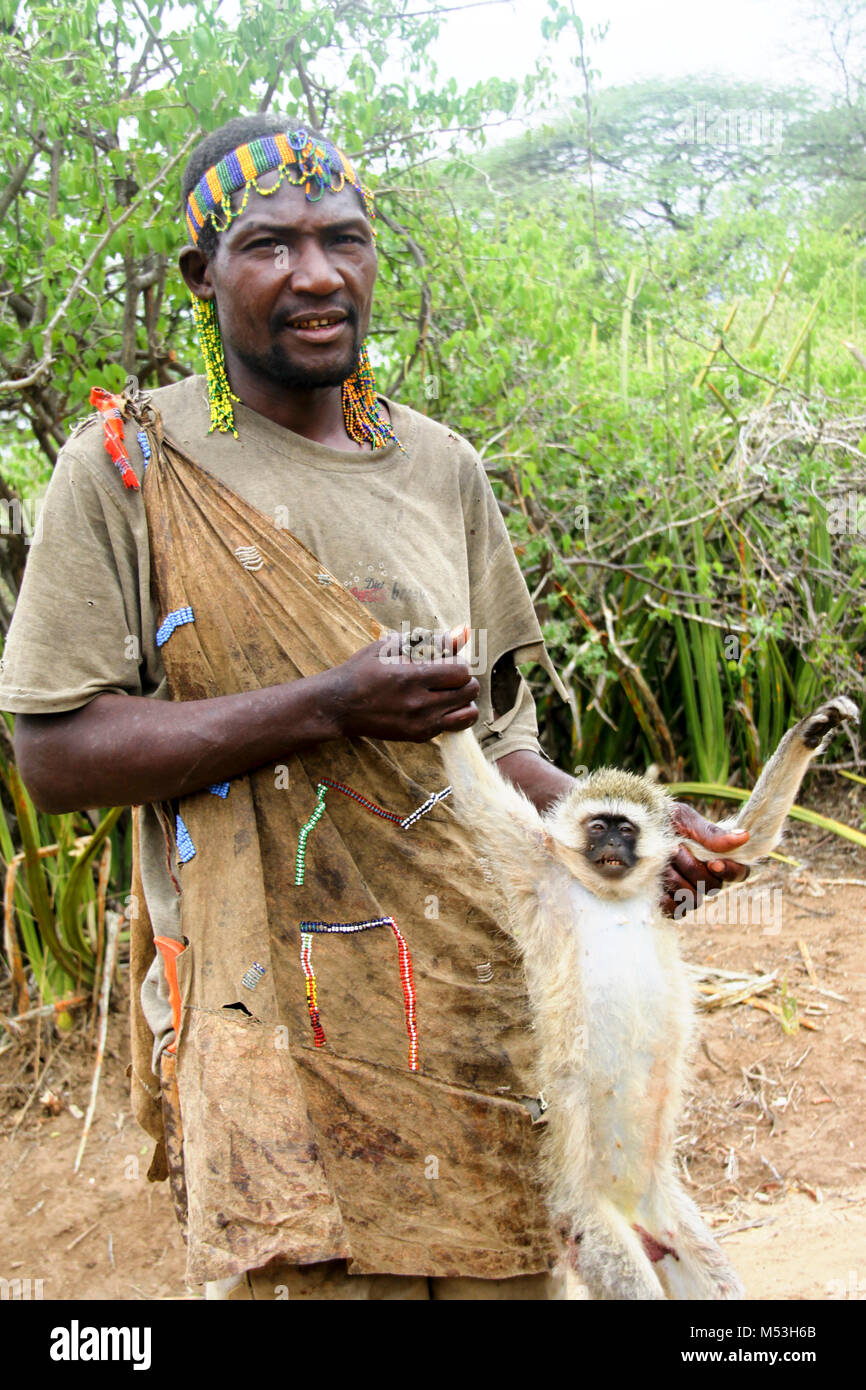 Un cacciatore Hadza ritorna al paese con una sua preda cacciata. Fotografato a lago Eyasi, Tanzania Foto Stock