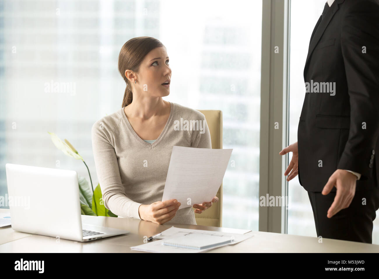 Giovane donna ascolto rivendicazioni sul suo lavoro da boss Foto Stock