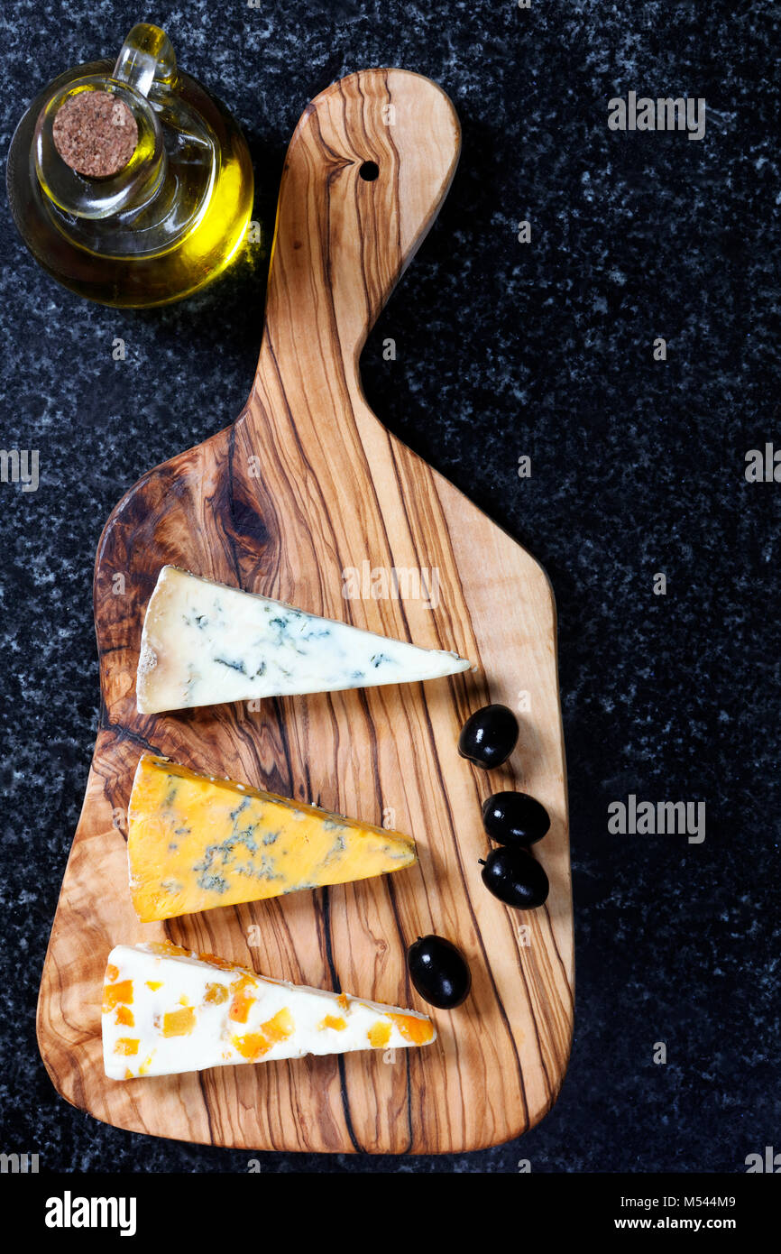 Cibo scuro - Stiltons blu e blu Shropshire formaggi su un'oliva pannello di legno Foto Stock