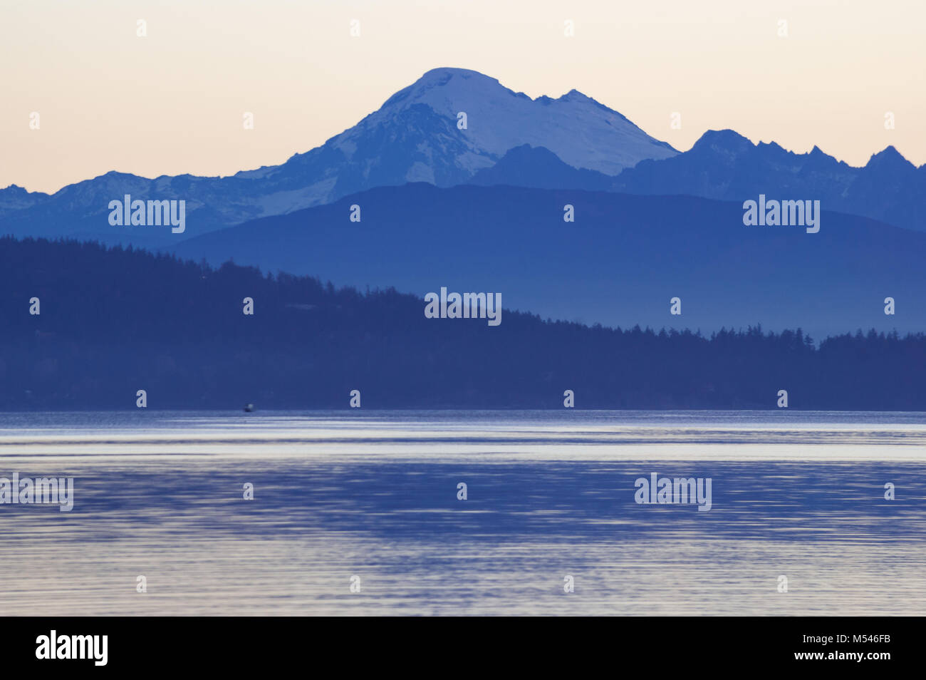 Mt Baker visualizzati in blu ora attraverso la mattina calma acqua del Puget Sound dal traghetto a Anacortes, Stati Uniti di Washington Foto Stock