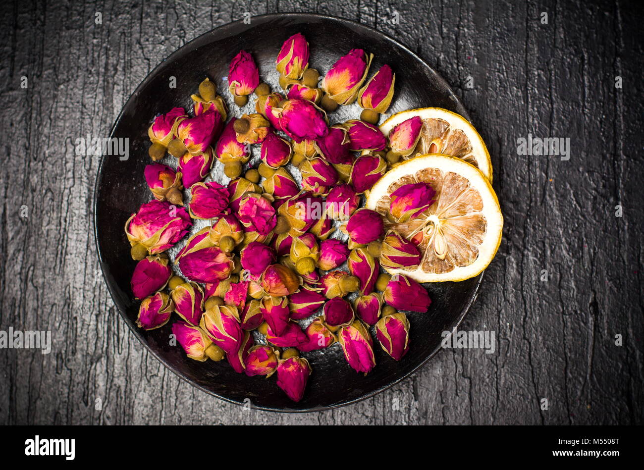 Rosa tea le gemme e le fette di limone sulla piastra scuro Foto Stock