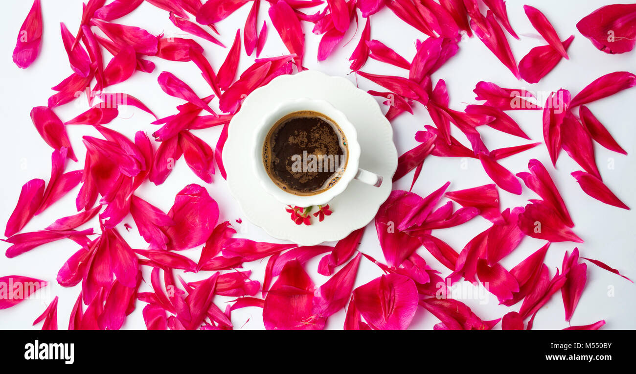 Tazza di caffè circondato da red petali di fiori Foto Stock