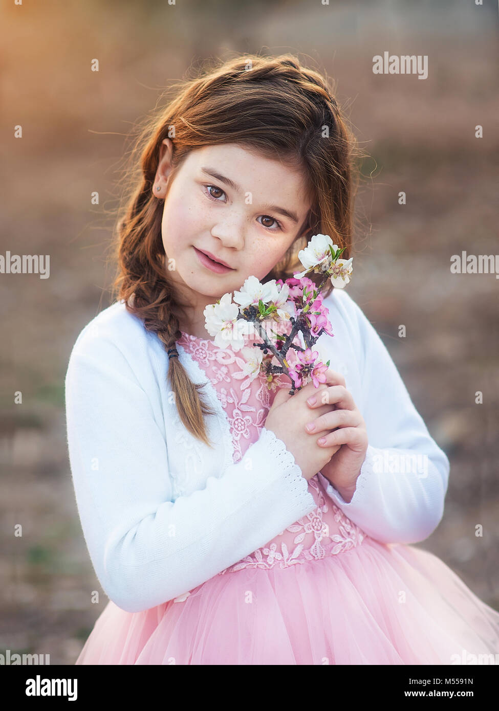 Bambina con fiori di mandorlo nei giardini Foto Stock