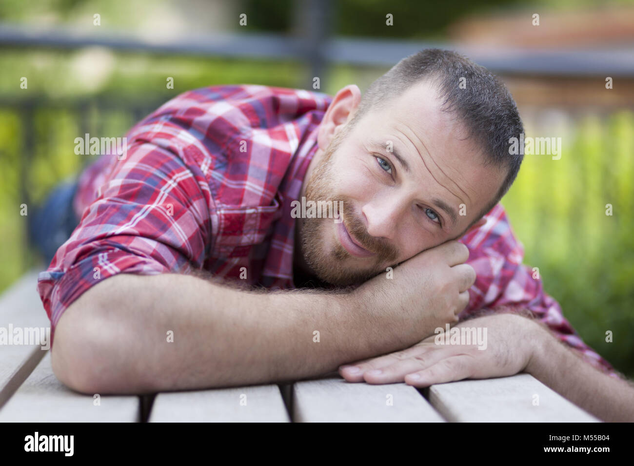 Barbuto uomo bello giacente su un banco di lavoro Foto Stock