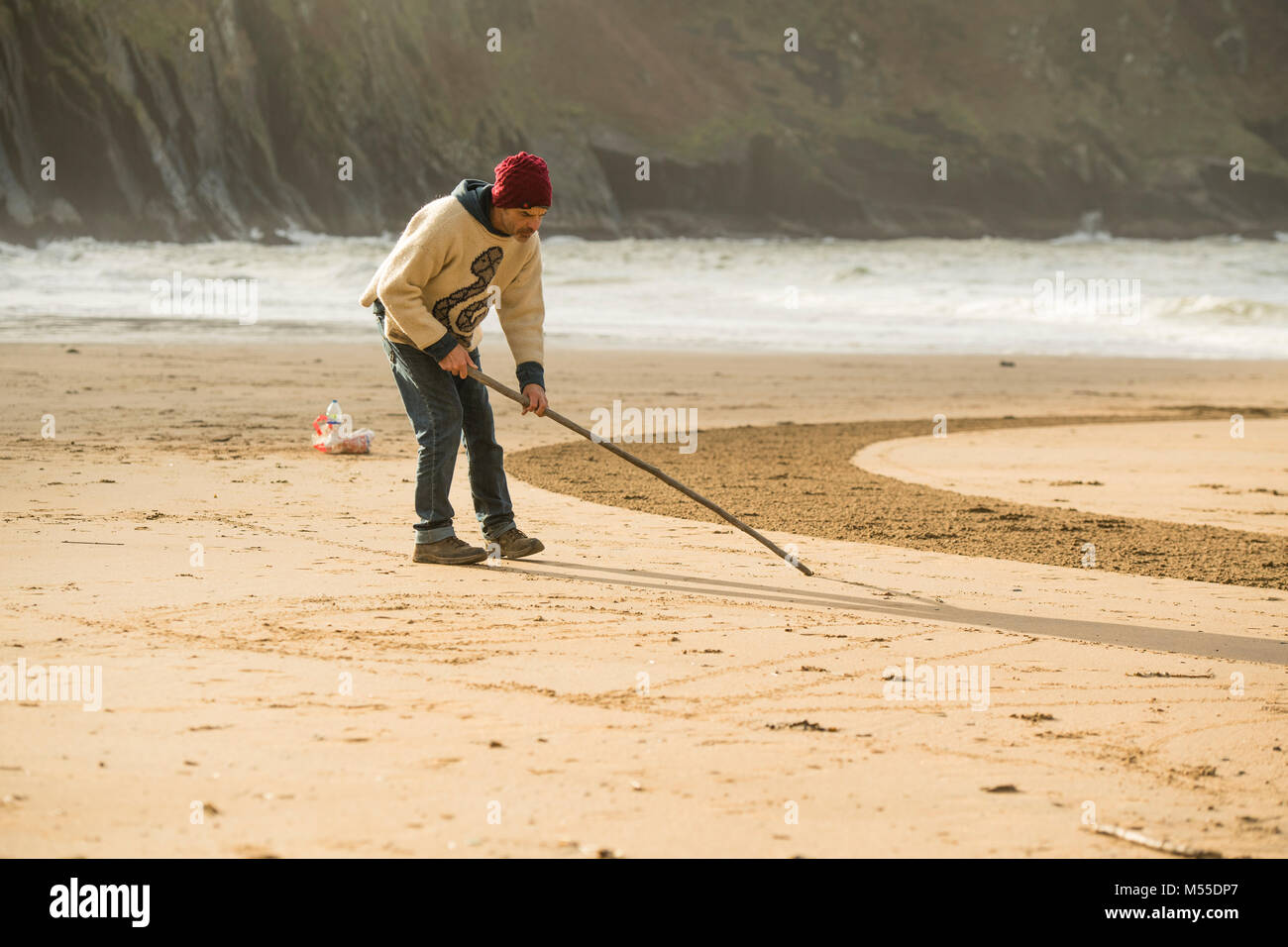 MARC TREANOR, sabbia artista, lavorando su una delle sue enormi , ma effimero, geometriche graphic design e modelli su una spiaggia di sabbia in Mwnt, West Wales UK, prima che la marea entra e lava via tutto Foto Stock