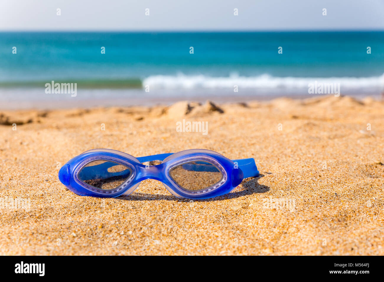 Blue occhiali da nuoto giacenti presso la spiaggia con vista mare Foto Stock