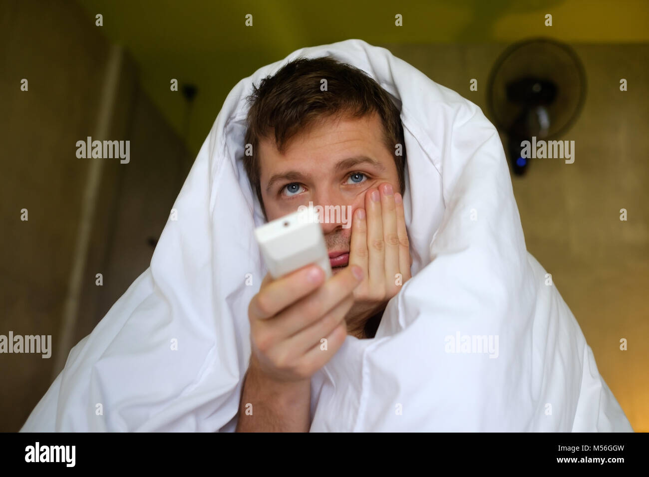 Giovani caucasici uomo annoiato guardando la TV seduti a casa soggiorno cercando stanco Foto Stock