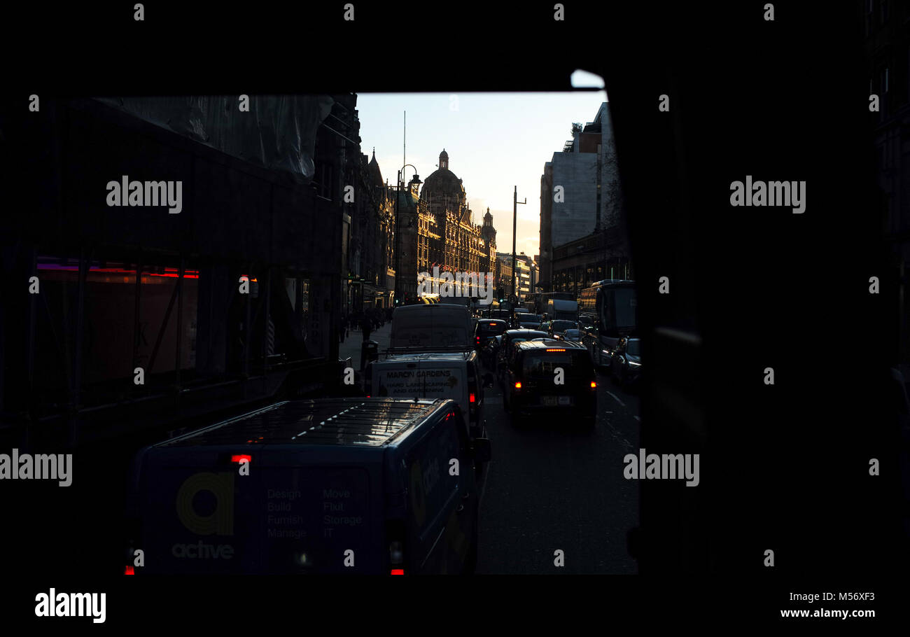 Una drammatica POV dalla strada sopra le vetture osservando il traffico verso i magazzini Harrods di Brompton Road Londra in serata luce dorata come il sole tramonta Foto Stock