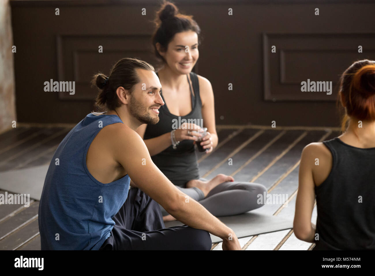 Memore sorridente yogi uomo seduto sul tappetino in un training di gruppo Foto Stock