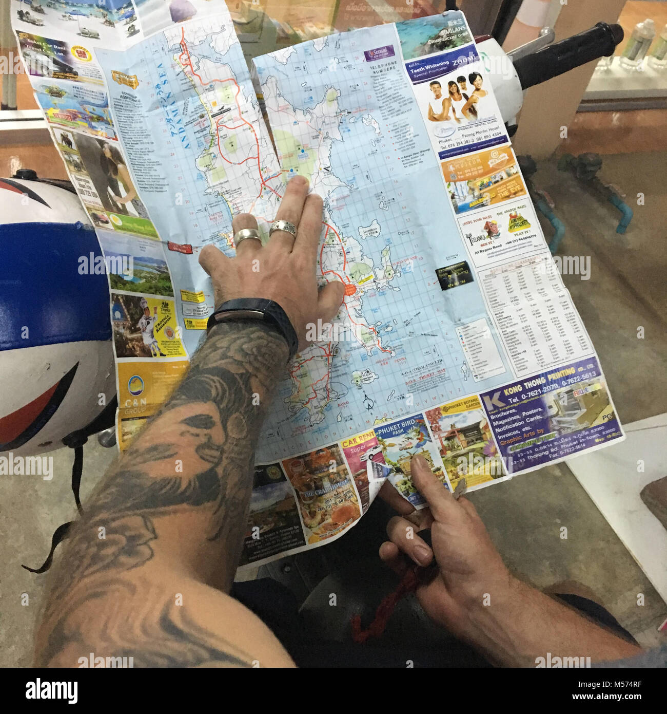 Perso il bianco maschio caucasico mano azienda mappa dell'isola di Phuket cercando per il percorso di viaggio Foto Stock