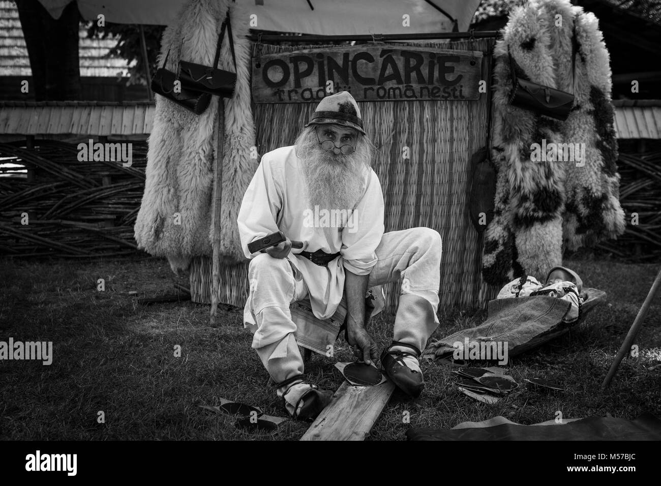 Il rumeno uomo in abito tradizionale a mano in pelle rendendo le merci presso il museo del villaggio a Bucarest Foto Stock