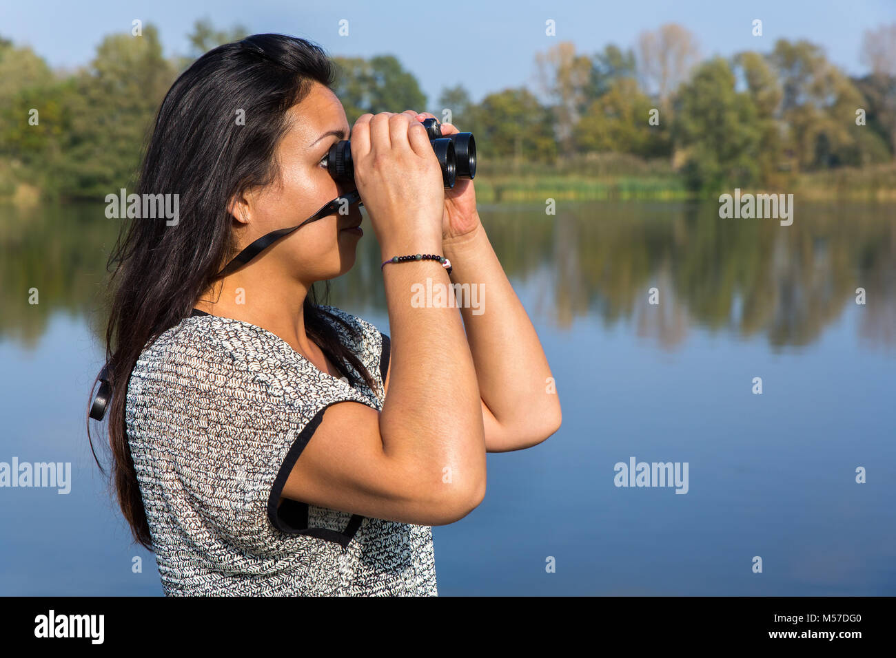 Donna che guarda attraverso il binocolo ad acqua Foto Stock