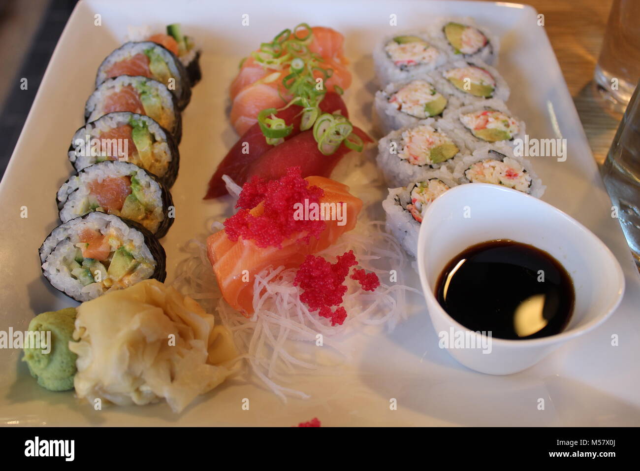 Quadrato grande piastra bianca Mostra 20 elementi di sushi, decapati zenzero, wasabi e salsa di soia in una piccola ciotola Foto Stock