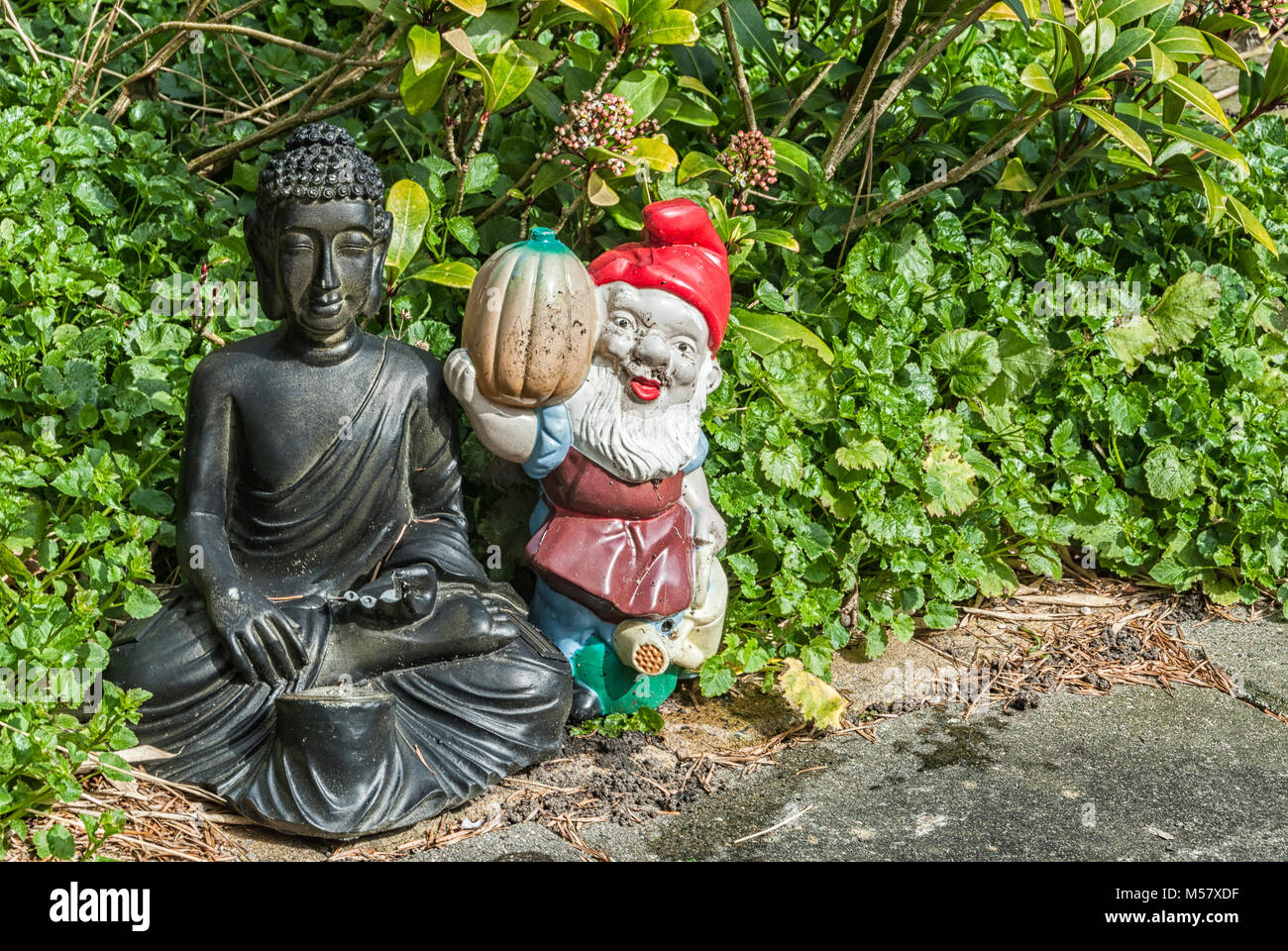 Buddha e gnome pavimentato in un giardino Foto Stock